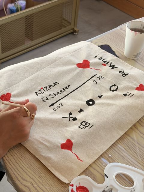 Painting a music-inspired tote bag at the workshop table