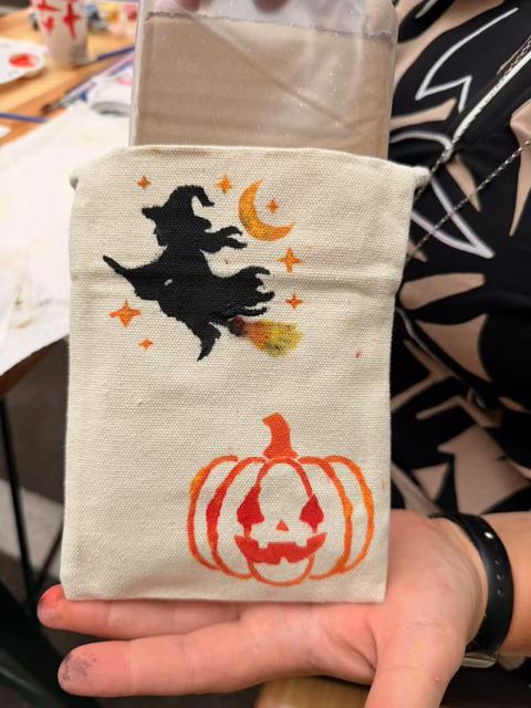 Small bag painted with a witch on a broom and a jack-o'-lantern