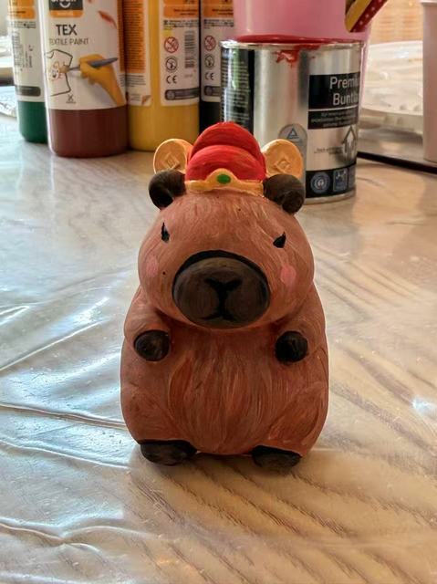Painted plaster capybara wearing a red hat